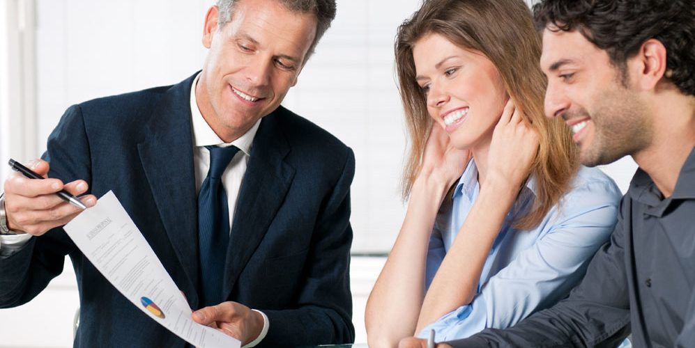 Photo of a man and woman meeting with a male advisor, looking at a financial pie chart