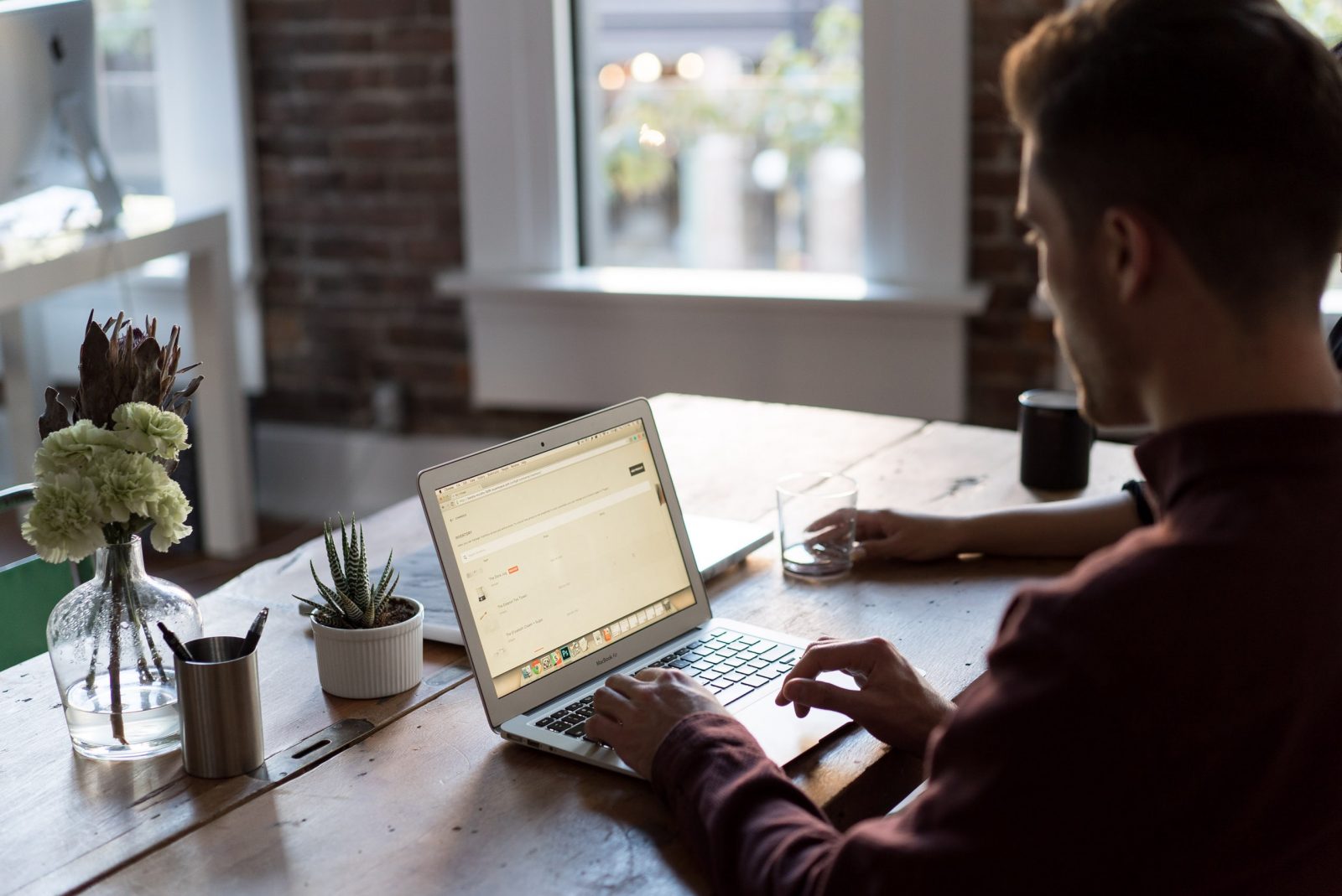 Photo of a man at a work table using a laptop computer